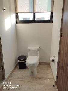 a bathroom with a toilet and a window at Departamento en Punto Horizonte, Sonata Puebla in Lomas de Angelopolis