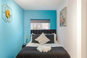 1 dormitorio con paredes azules y 1 cama con 2 toallas en Diamond Suite Camden Town 3 Bedroom Sleeps 11 en Londres