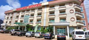 un hôtel avec des voitures garées devant un bâtiment dans l'établissement Adamaoua Grand Hôtel Aéroport, à Douala