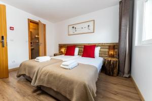 2 camas en una habitación de hotel con almohadas rojas en Olá Vida - Hostel Caminha en Caminha
