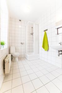 a white tiled bathroom with a shower and a toilet at Green Hostel in Toruń