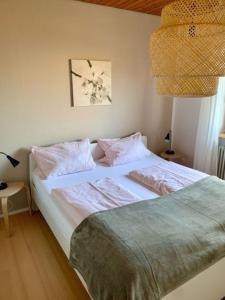 um quarto com uma cama grande com lençóis brancos e almofadas em Haus Elstar em Bodman-Ludwigshafen