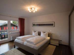 een slaapkamer met een bed en een groot raam bij Schöne Wohnung in Garmisch-Partenkirchen und Bergblick in Garmisch-Partenkirchen