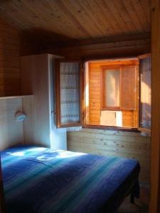 a bedroom with a bed and a window at Holzchalet mit überdachter Veranda und Terrassenmöbeln auf einem schönen Campingplatz in Viareggio