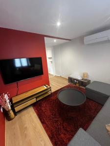 a living room with a flat screen tv on a red wall at Agréable Appartement Centre B in Bourges