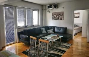 salon z czarną skórzaną kanapą i stołem w obiekcie Amazing View City Square Apartment w mieście Skopje