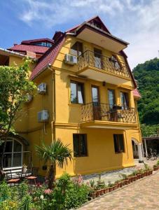 um edifício amarelo com uma varanda numa rua em Deluxe guest house em Kvariati