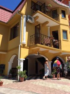 dwoje ludzi idzie przed żółtym budynkiem w obiekcie Deluxe guest house w mieście Kvariati