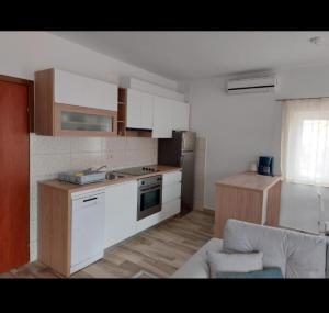 Apartments Ivanovski في راب: مطبخ مع دواليب بيضاء واريكة في الغرفة