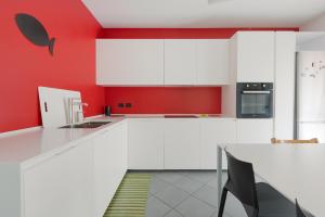 a kitchen with white cabinets and a red wall at [Niguarda] - Ampio e Moderno Trilocale in Milan