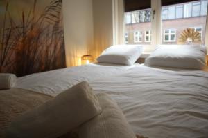 dwa duże białe łóżka w pokoju z oknem w obiekcie Knus appartement Tilburg w mieście Tilburg