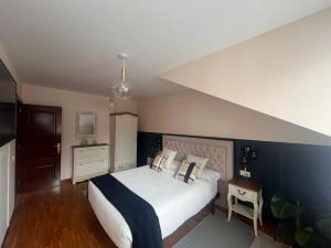 a bedroom with a white bed with a blue wall at Maison Villaviciosa Asturias in Villaviciosa