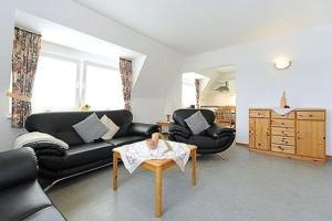 una sala de estar con 2 sofás de cuero negro y una mesa. en Deichblick, en Esens