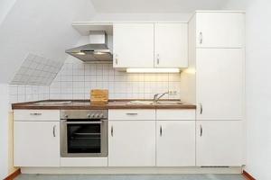 Una cocina blanca con gabinetes blancos y un fregadero. en Deichblick, en Esens