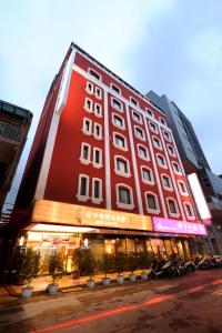 台北的住宿－府中棧精品商旅，一座大型红色建筑,前面停有摩托车