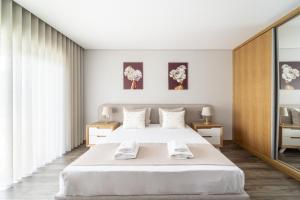 um quarto com uma grande cama branca e duas mesas em Casa Eido Doce by House and People em Barcelos