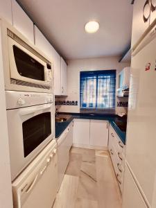 una cocina con armarios blancos y electrodomésticos blancos en Apartamento Empul Costa Sancti Petri en Chiclana de la Frontera