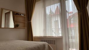 een slaapkamer met een bed en een groot raam bij Апартамент Касъл in Pamporovo