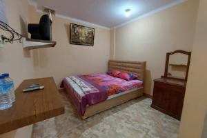 1 dormitorio con cama, mesa y espejo en OYO 93757 Rasya Homestay en Midang