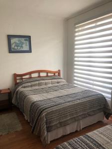 a bedroom with a bed and a window with a blanket at San Sebastian in Concepción