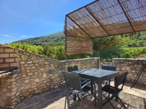 una mesa y sillas en un patio con una pared de piedra en gîte Les Pégots - studio en Ménerbes