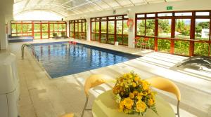 a large swimming pool with a table and flowers on it at Hotel Casa de los Fundadores in Villa de Leyva