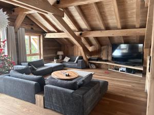 uma sala de estar com sofás, uma mesa e uma televisão em Chalet Clémence em Taninges