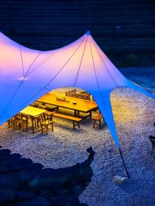 Tienda grande con mesa y bancos por la noche en Zhangjiajie National Forest Park Camping en Zhangjiajie