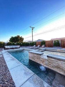 una piscina en un patio con bancos alrededor en Casa Malia -salt water oasis en Desert Hot Springs