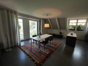 a living room with a table and chairs and windows at L'Eau Forte - maison d'hôtes in Saint-Blaise