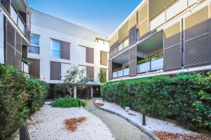 un immeuble avec des buissons et une cour dans l'établissement T2 Florescence Proche Montpellier Parking, à Castelnau-le-Lez