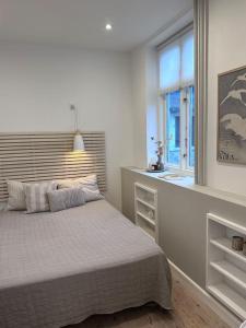 a white bedroom with a bed and a window at City center apartment w/ large private balcony in Aalborg