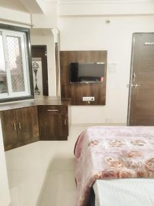 Schlafzimmer mit einem Bett, einem TV und einem Fenster in der Unterkunft Hotel Shree chandram - 10min walking distance to श्रीNathji temple in Nāthdwāra