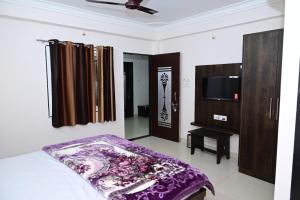 a bedroom with a bed and a flat screen tv at Hotel Shree chandram - 10min walking distance to श्रीNathji temple in Nāthdwāra