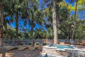 a deck with chairs and a swimming pool with trees at Nature’s Haven in Kiawah Island