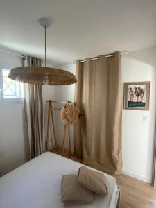a bedroom with a bed and a chandelier at T2 Dans le vent Gruissan bord de mer in Gruissan