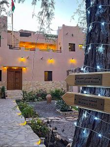 um sinal numa árvore em frente a um edifício em Omani House Inn نزل البيت العماني em Nizwa