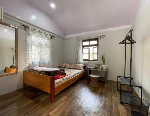 a bedroom with a bed and a desk and a window at Pakha Dhim Heritage Homestay in Namchi