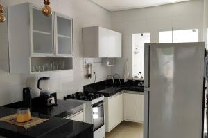 a kitchen with white cabinets and a stainless steel refrigerator at Casa aconchegante, 1 suit e 2 quartos/escritório. in Petrolina