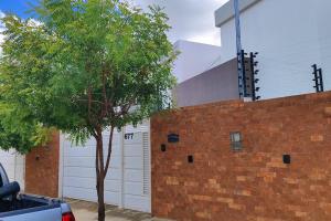 una pared de ladrillo con un garaje y un árbol en Casa aconchegante, 1 suit e 2 quartos/escritório. en Petrolina