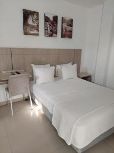 ein Schlafzimmer mit einem großen weißen Bett und einem Tisch in der Unterkunft Hotel Zamay in Santa Marta