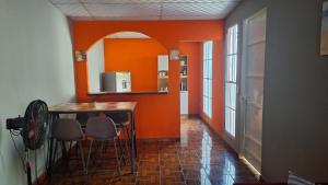 Yanira's house في سانتا آنا: مطبخ بجدران برتقالية وطاولة وكراسي