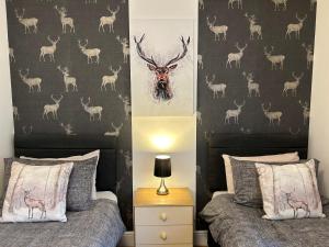 1 dormitorio con 2 camas y una pared con cabezas de ciervo en Solway Cottage en Annan