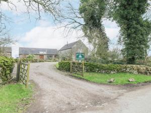 a dirt road in front of a house with a gate at Dove Cottage in Leek