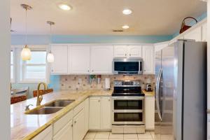 uma cozinha com armários brancos e um frigorífico de aço inoxidável em Home by the Sea em Surf City