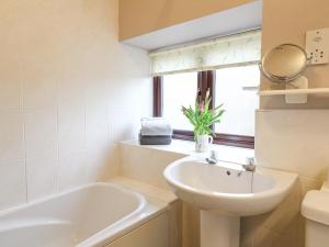 a bathroom with a sink and a tub and a mirror at Dove Cottage in Leek +15 photos