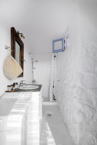 a white bathroom with a sink and a mirror at La Casa del Pastore in Serifos Chora