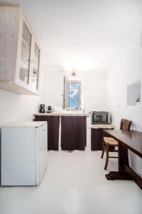a white kitchen with a table and a refrigerator at La Casa del Pastore in Serifos Chora