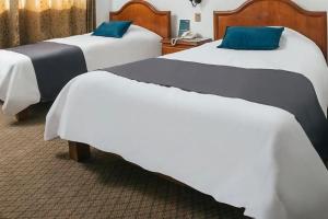 una camera d'albergo con due letti con cuscini blu di Hotel Asturias ad Arequipa