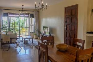 uma cozinha e sala de jantar com uma mesa de madeira e cadeiras em The Greenleaf Apartment, Lubowa. em Kampala